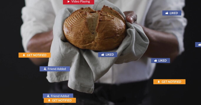 Baker wearing white shirt holding towel wrapped bread in studio, with floating social media icons - Powered by Adobe