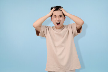 frustrated young man yelling in anger against a blue background