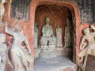 Buddha, Disciples, Bodhisattvas, two guardian warriors in Weikang Grotto at Thousand-Buddha Cliff in Guangyuan, Sichuan, China, constructed from late Northern Wei Dynasty.