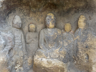 Weathered statues of Buddha, disciples and Bodhisattvas in a greeto at Thousand-Buddha Cliff on bank of Jialing River in Guangyuan, Sichuan, China, constructed from late Northern Wei Dynasty.