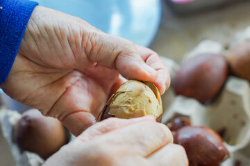 Hands peeling a marbled brown boiled egg, known as Telur Pindang, revealing smooth egg white