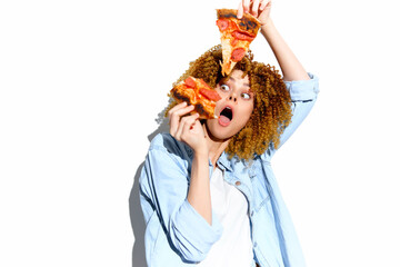 Excited young woman with curly hair holding slices of pizza, expressing joy and surprise against a white background, perfect for food enthusiasts and healthy eating concepts