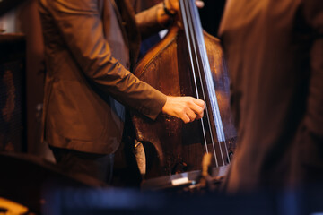 Concert view of contrabass violoncello player with vocalist and musical rock band during concert, jazz orchestra performing music, violoncellist cello jazz player on stage in a club, music arena hall