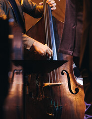 Concert view of contrabass violoncello player with vocalist and musical rock band during concert, jazz orchestra performing music, violoncellist cello jazz player on stage in a club, music arena hall