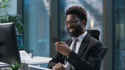 Happy African American man using credit card banking employee typing computer male paying purchase businessman smiling business guy in office online shopping client buying ecommerce app entrepreneur