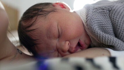 Newborn baby sleeping contentedly on mother’s chest, capturing a peaceful moment of bonding and...