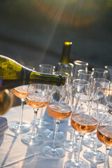 Rosé wine being poured into crystal glasses on a festive outdoor table in warm sunlight.
Tags:...
