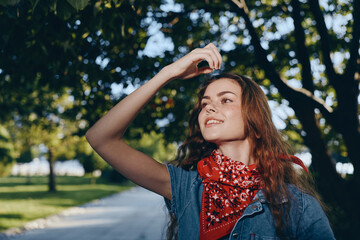 Naklejka premium lifestyle woman in modern boho-western denim street style with red bandana enjoying sunny outdoor urban park in film color