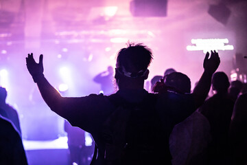 Adult Worshiping with Arms Raised in Room Lit with Stage Lighting