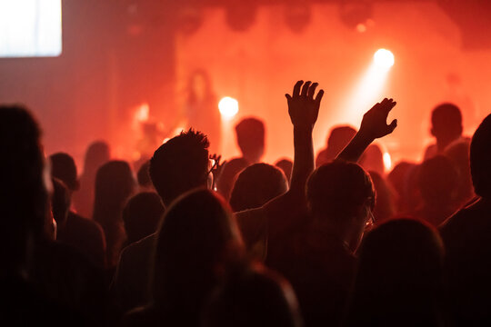 Man in Glasses Worshipping Under Orange Stage Lighting