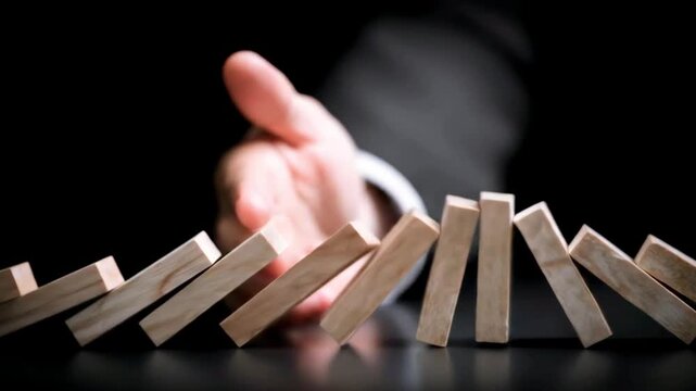 Businessman stopping falling wooden blocks symbolizing risk management and decision-making process