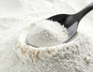 A spoonful of powdered milk on a pile of powdered milk.
