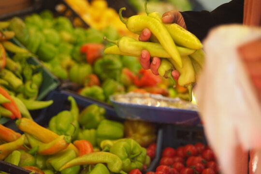 woman buying Colorful variety of peppers at a bustling market stand
