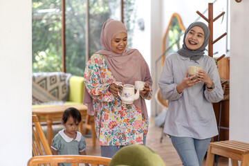 Indonesian Muslim women enjoying drinks indoors with a child