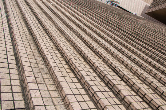 Building exterior stairs with antique red brown granite tiles. Structure of brick tile paved staircase amidst bright sunlight. For people traveling up and down. Arranged in same pattern. - Powered by Adobe