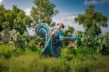 Traditional Mexican folkloric dancer with turquoise dress and cactus landscape
