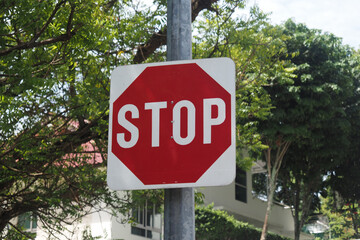 Red stop sign situated on a quiet street surrounded by trees