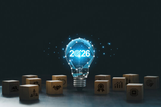 Futuristic light bulb with 2026 and a bullseye glows above wooden blocks of strategy icons, symbolizing innovation, business goals, AI, growth, quality and sustainability for planning and success.