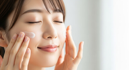 スキンケア化粧品を顔に塗る若い女性