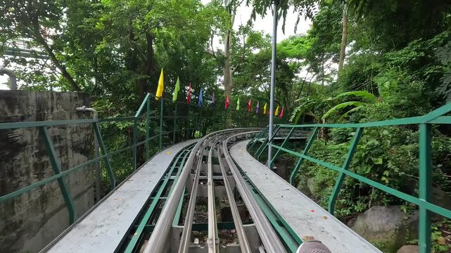POV shot of an alpine roller coaster descending through lush greenery on Ba Den Mountain in Tay Ninh, Vietnam.	
