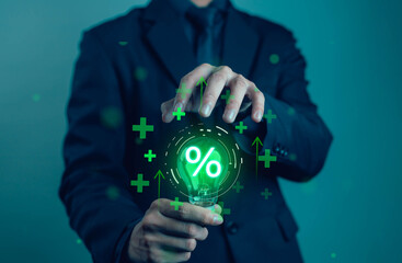 Businessman holding a glowing light bulb with percentage symbol, representing financial growth,...