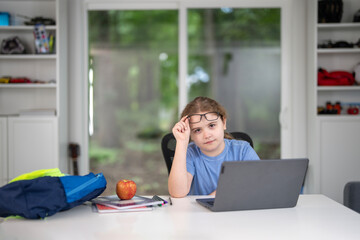 Child study at home with laptop and books. Kid learning in a cozy home classroom. Kid study at classroom. Online learning. Studying concept. Child study at home. Boy doing school homework.