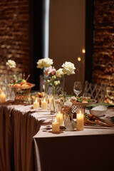 Wedding banquet table decorated with candles, flowers and food in elegant restaurant interior with brick wall. Concept of celebration, romance, reception, event decoration.
