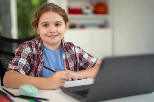 Child study at home with laptop and books. Kid learning in a cozy home classroom. Kid study at classroom. Online learning. Studying concept. Child study at home. Boy doing school homework.