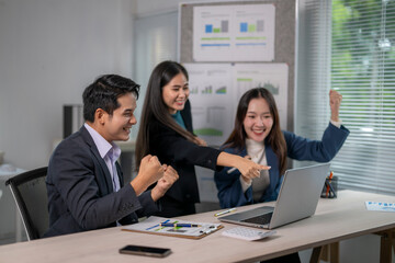 Three people are celebrating in a business setting