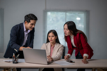 Three people are sitting at a desk with a laptop open