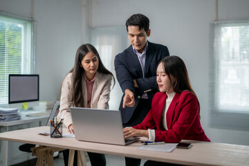 Three people are sitting at a desk with a laptop open