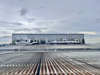 Wide view of industrial factory rooftop with ventilation ducts, pipelines, and dust collection systems for air treatment, energy efficiency, and environmental control.