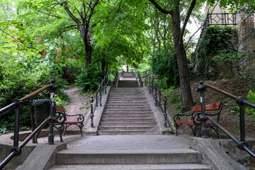 Budapest, Hungary – View of stone stairs lined with benches and trees on the way to the Castle District, a leafy pedestrian path leading to historic landmarks.