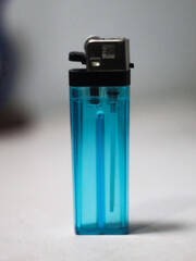 This photo shows a blue transparent gas lighter with a silver metal head. The lighter stands...