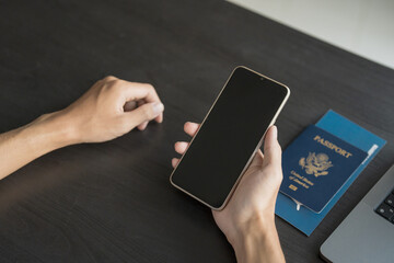 Hand Man Online booking and buying plane tickets using laptop phone and credit card Planning trip travel vacation with passport and ticket