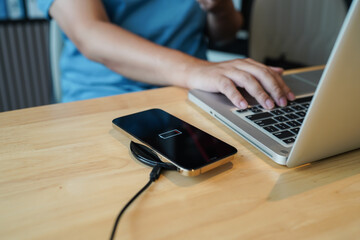 Charging mobile phone battery with wireless charging device in the table. Smartphone charging on a...