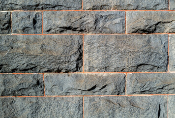 Charcoal Grey Rough Hewn Granite Wall with Red Mortar.