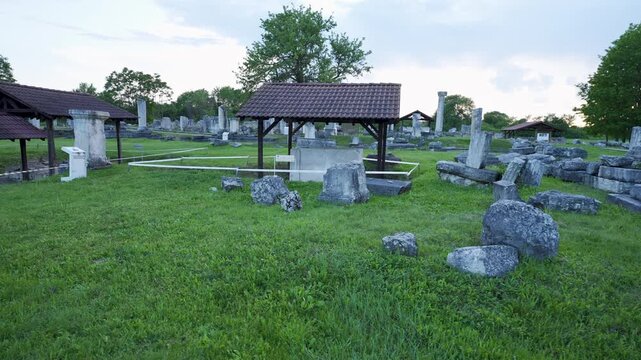 Ancient ruins at Nicopolis ad Istrum, featuring scattered columns, stone blocks, and a covered artifact