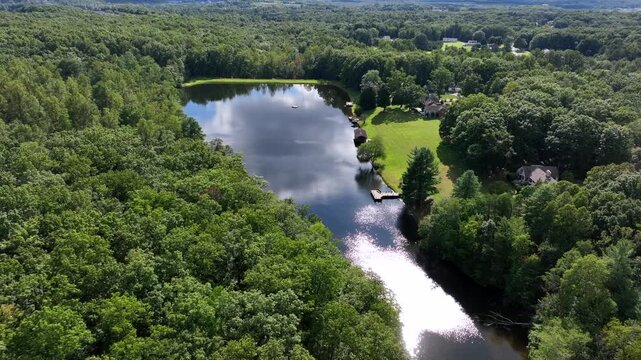 Small river lake in scenic neighborhood of American town. Aerials approaching shot. Houses and homes with yards and lake access in Forest landscape of Virginia. Sunny Summer day in USA.