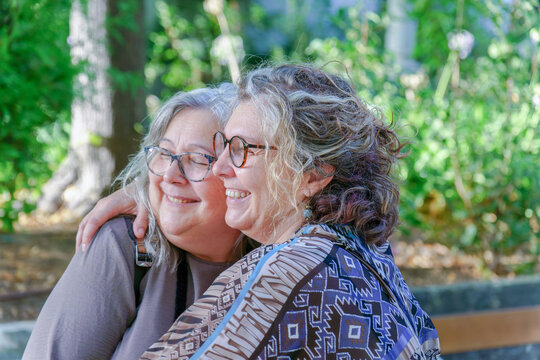 Two happy senior women hug in a park, enjoying a tender moment of affection and companionship, representing lgbtq love and visibility - Powered by Adobe