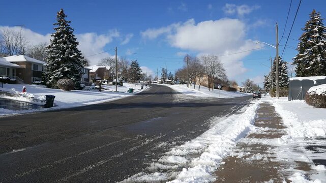 Looking up a snow winter road of a quiet suburban residential neighborhood in the Streetsville area of Mississauga, Ontario, Canada.