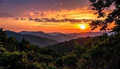 A breathtaking panorama of a vibrant sunset over a mountain range, bathed in warm hues and silhouetted by lush forests.
