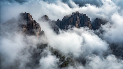 Jagged Mountain Peaks Emerging from a Sea of Clouds above aerial