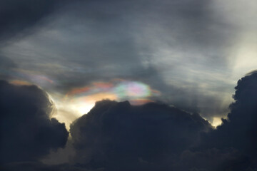 Beautiful Iridescent clouds over the dark sky. occur when sunlight diffracts off water droplets in the atmosphere.