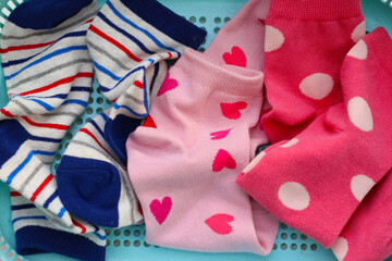 Fototapeta premium Mixed colorful socks with polka dot, stripe, and heart patterns in a laundry basket.