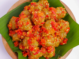 Spicy stir-fried fish balls coated with vibrant chili sauce, served on banana leaves for a bold and...