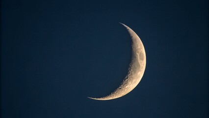 Crescent Moon Visible in Dark Blue Night Sky with Visible Craters image photo