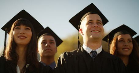 College, students and man with graduation, celebration and ceremony with achievement. Outdoor,...