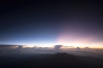Sunrise over a mountain range, viewed from above the clouds, showing a vibrant display of colors in the sky