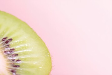 Close-up of a vibrant kiwi slice against a pale pink backdrop